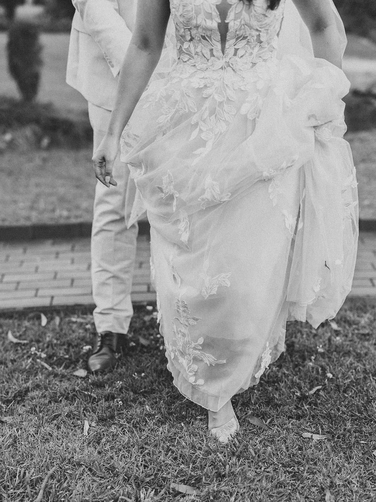 Black and white photograph of a bride holding her gown