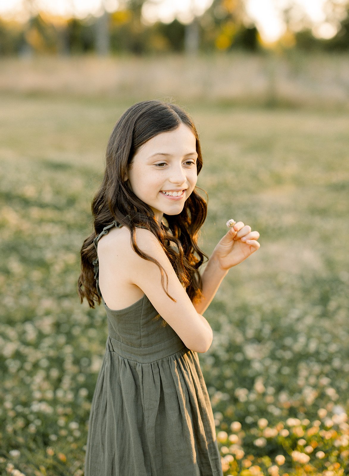 Young girl smiling in a green dress near yellow flowers