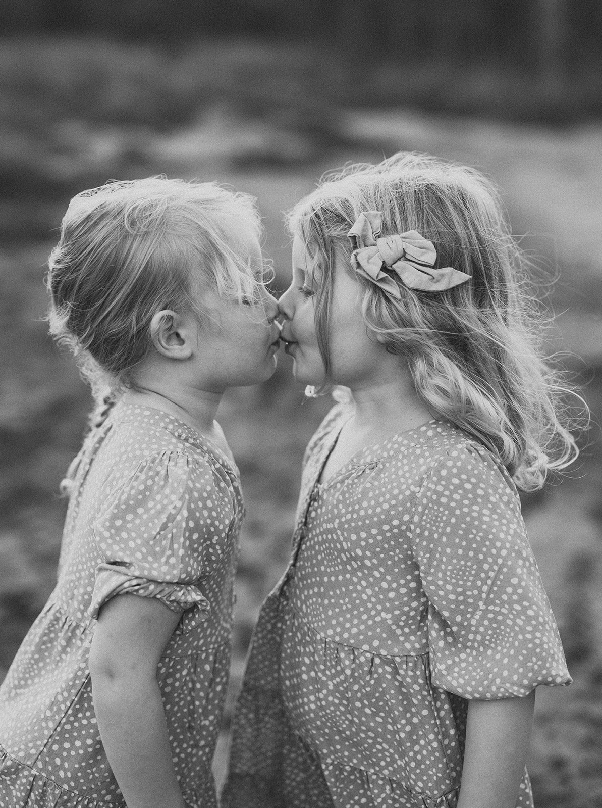 Black and white portrait of identical twin sisters kissing