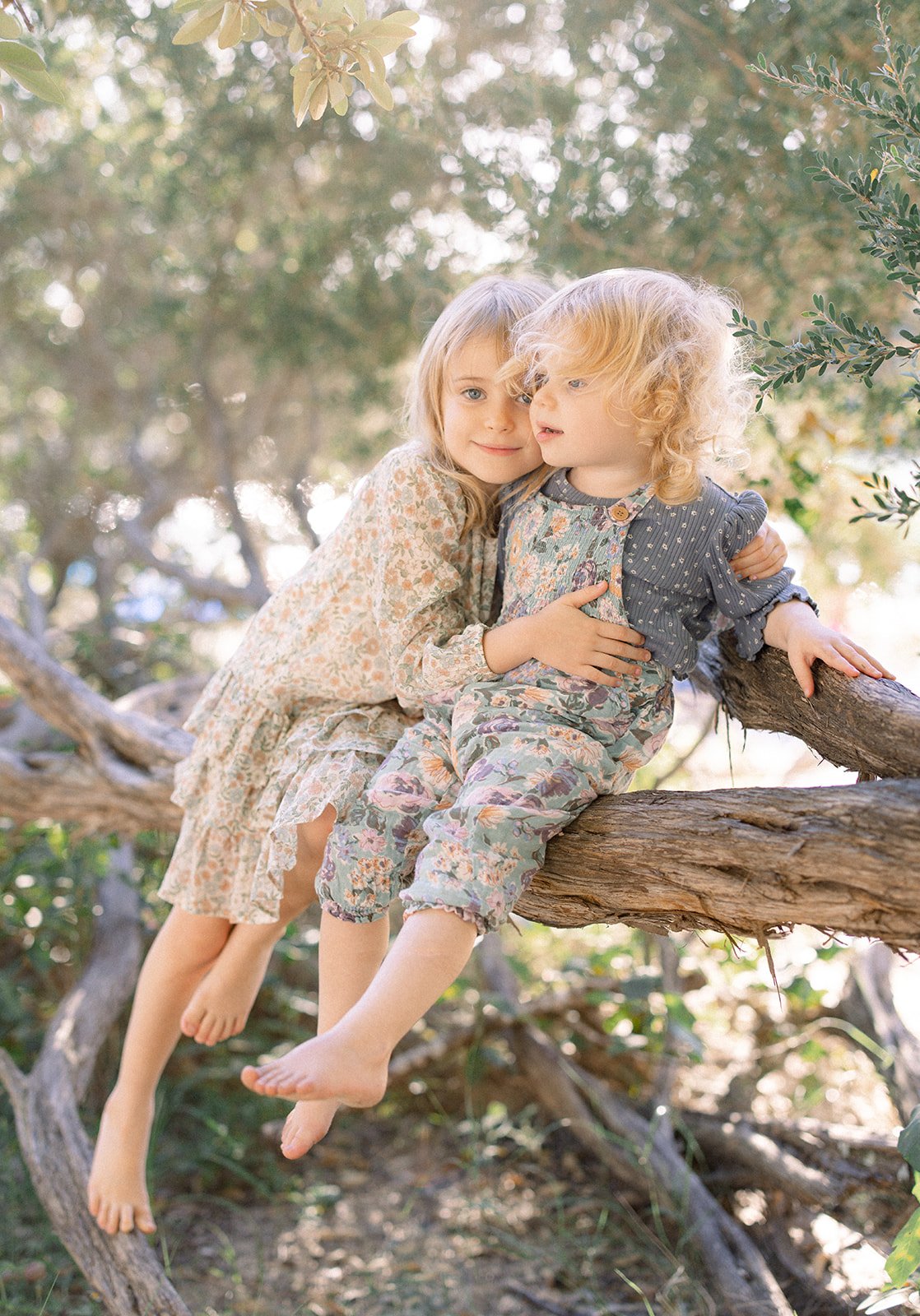 Sisters sitting side by side in a tree 