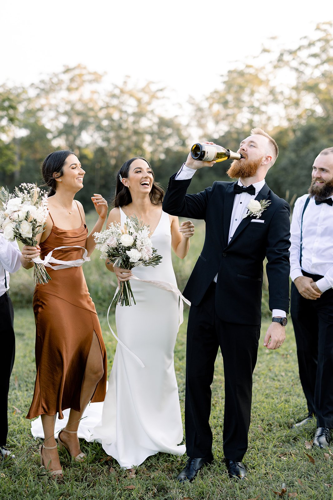 bridal party popping a bottle of champagne