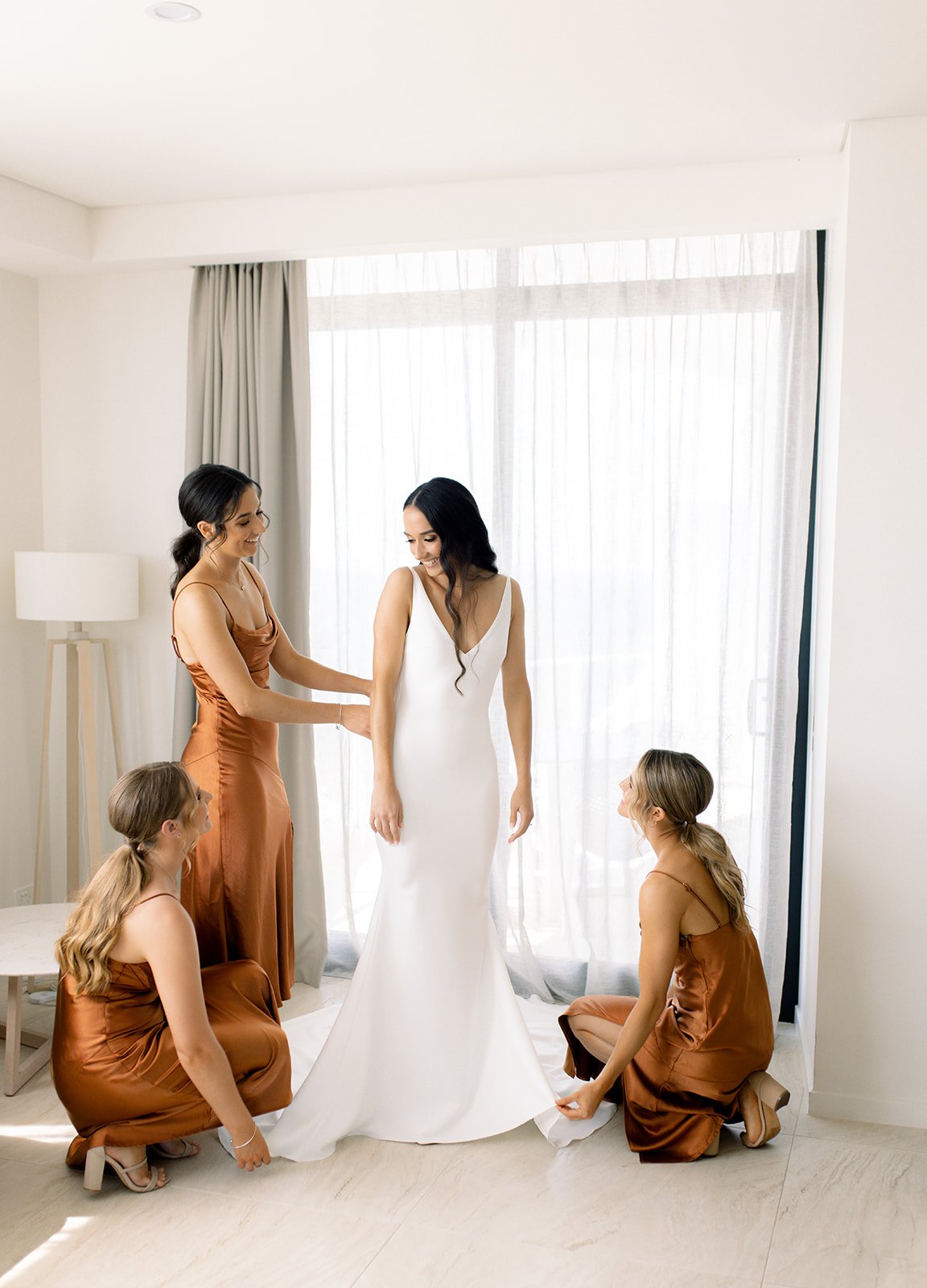 bridesmaids helping the bride get dressed on her wedding day