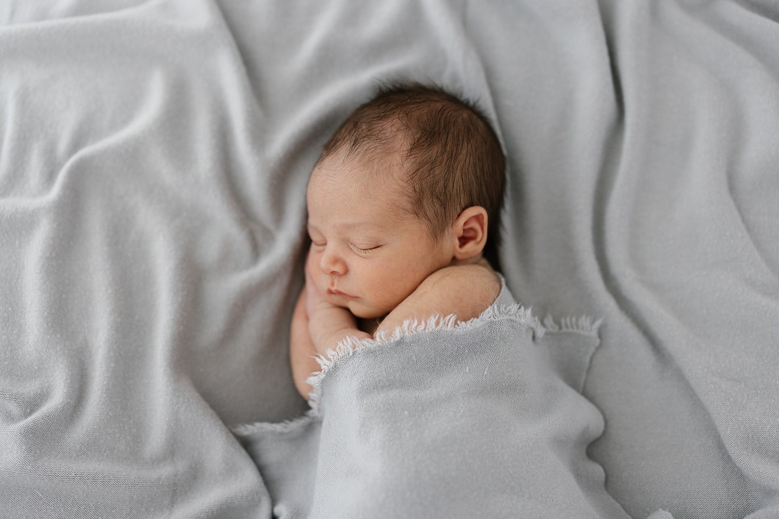 Newborn baby sleeping in a soft blue blanket