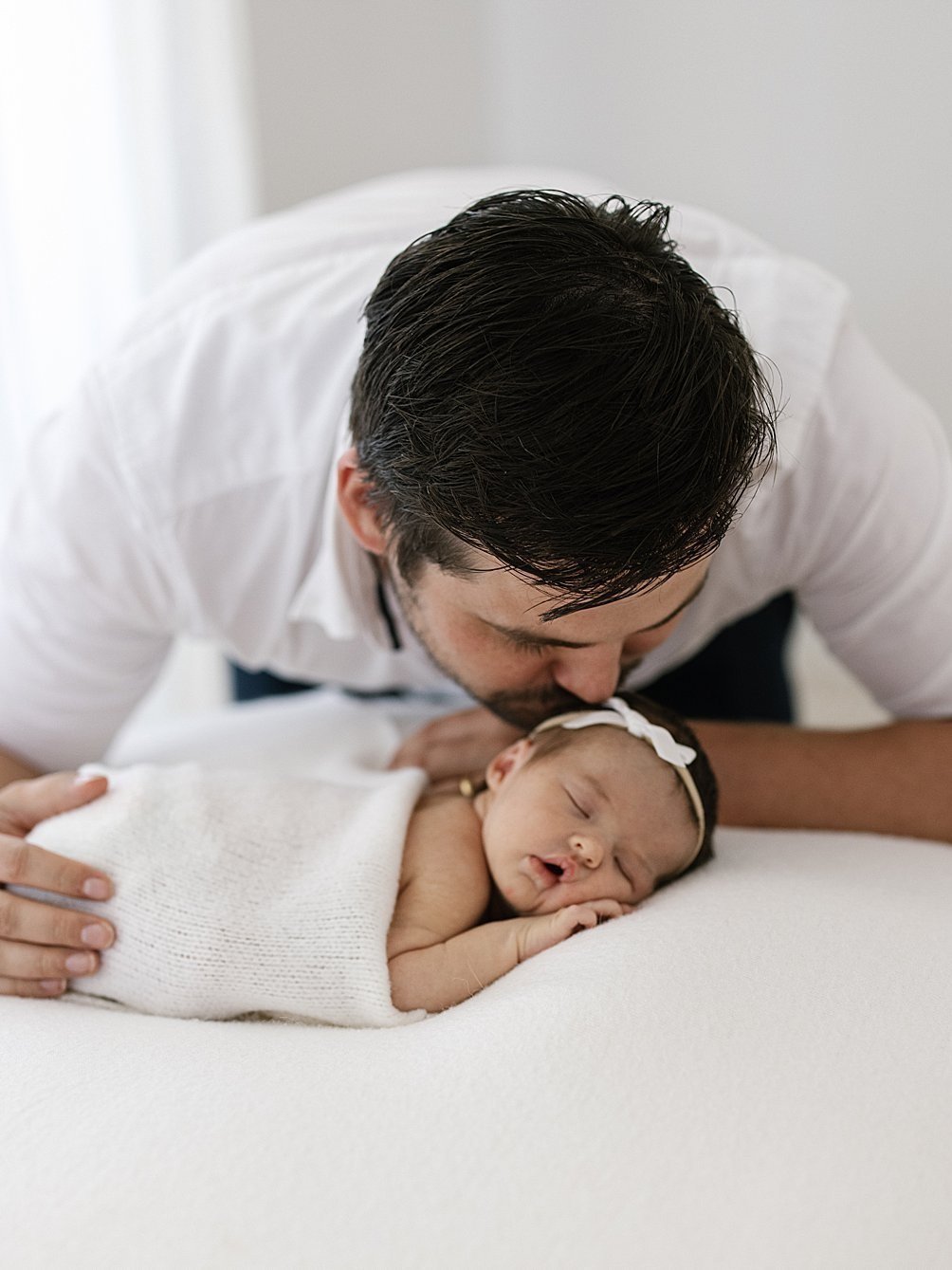 Father giving a kiss on his newborn daughter's head