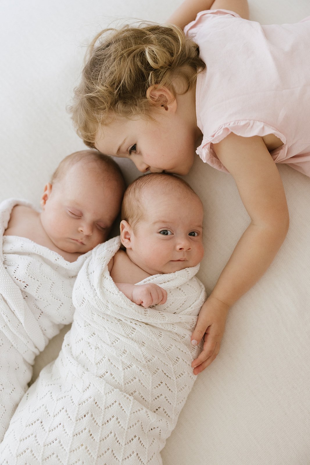 new big sister photographed kissing her newborn twin brothers 