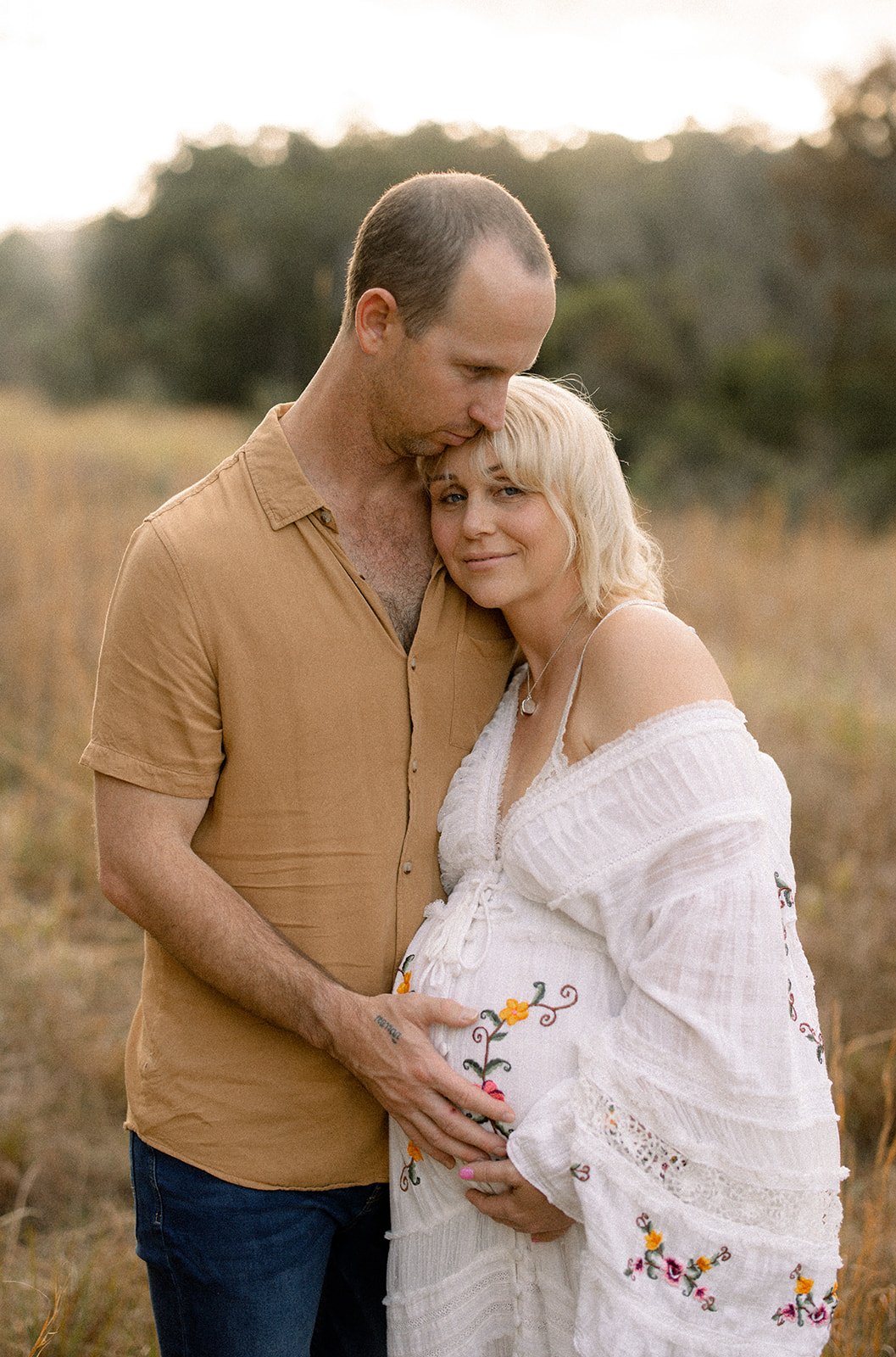 Dad photographed giving mums baby bump a gentle hold 