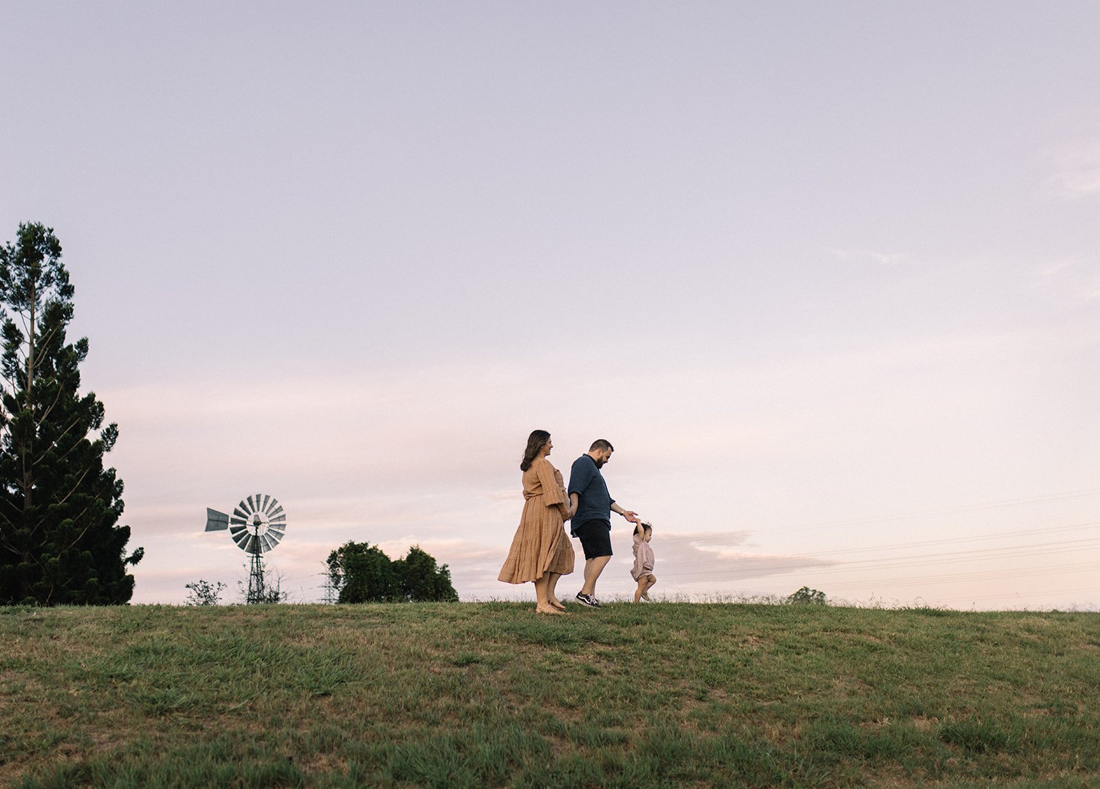 family photographed walking across a hill at sunset 