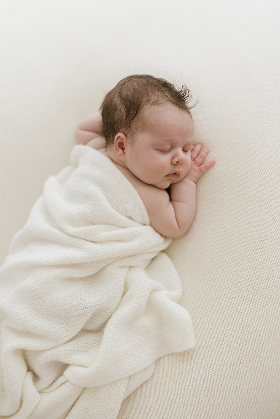 Newborn baby girl photographed in Brisbane baby studio cuddled in a white blanket 