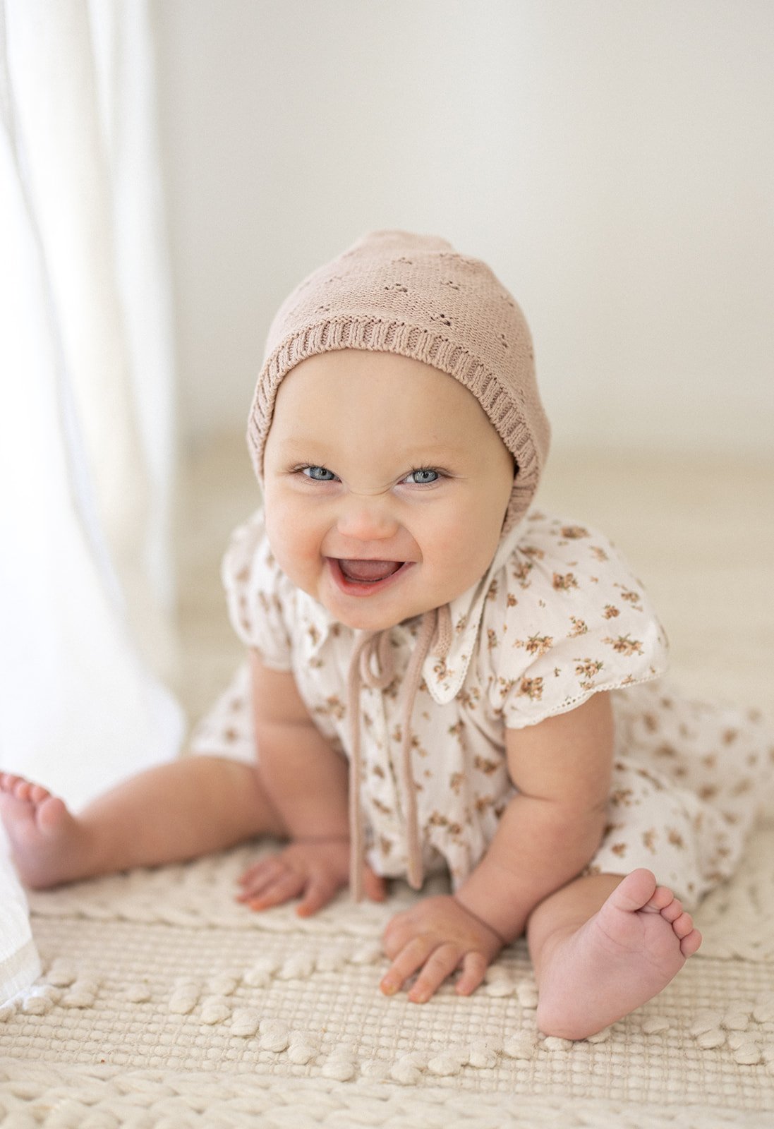 Baby girl sitting on blanket on the floor smiling