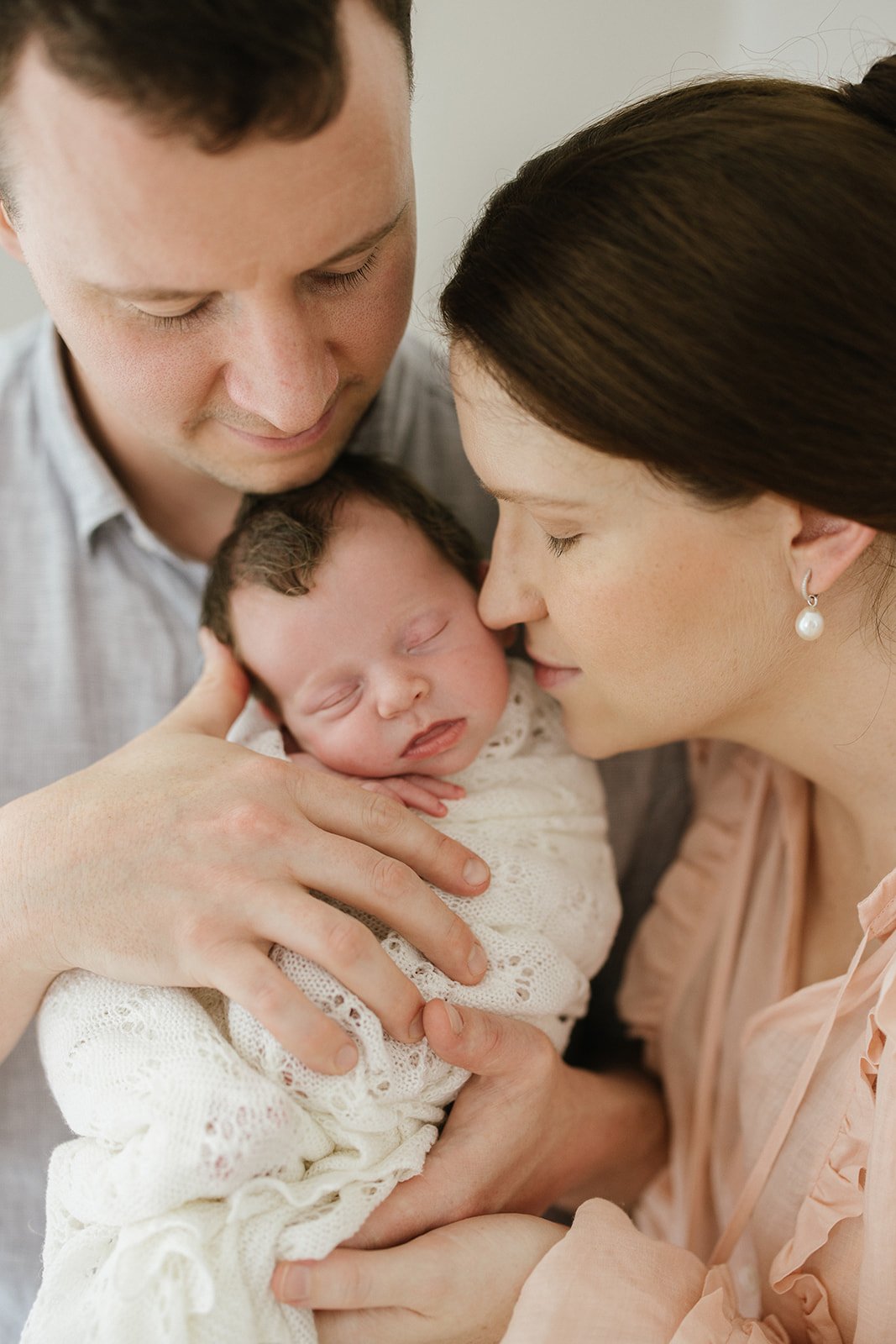 a mum and dad snuggle into their newborn baby daughter