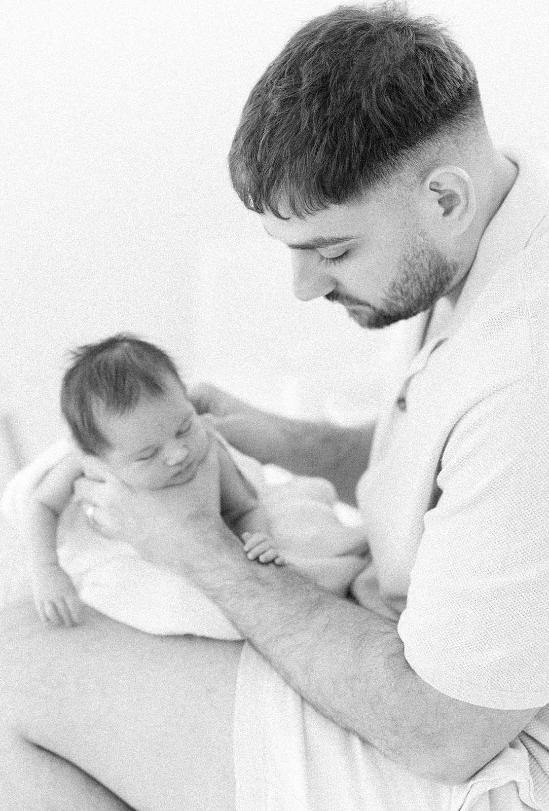 A black and white photo of a dad burping his newborn baby girl