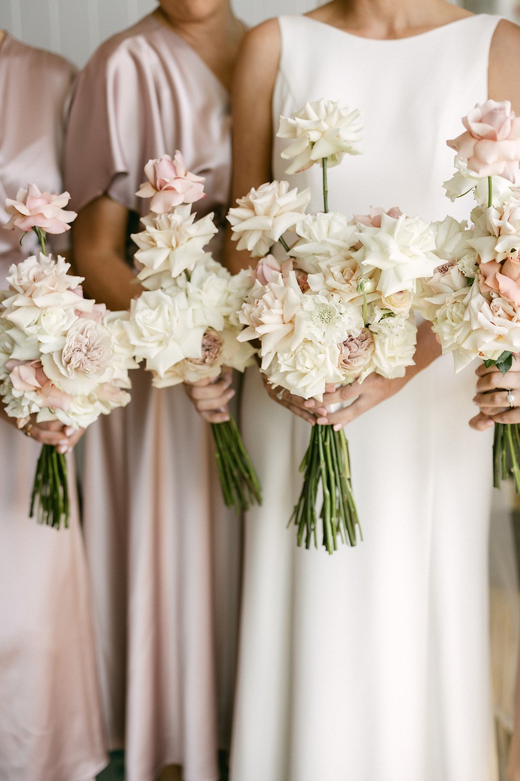 A photograph of a bride and her bridesmaids bouquets. They are a mix of soft pink and white