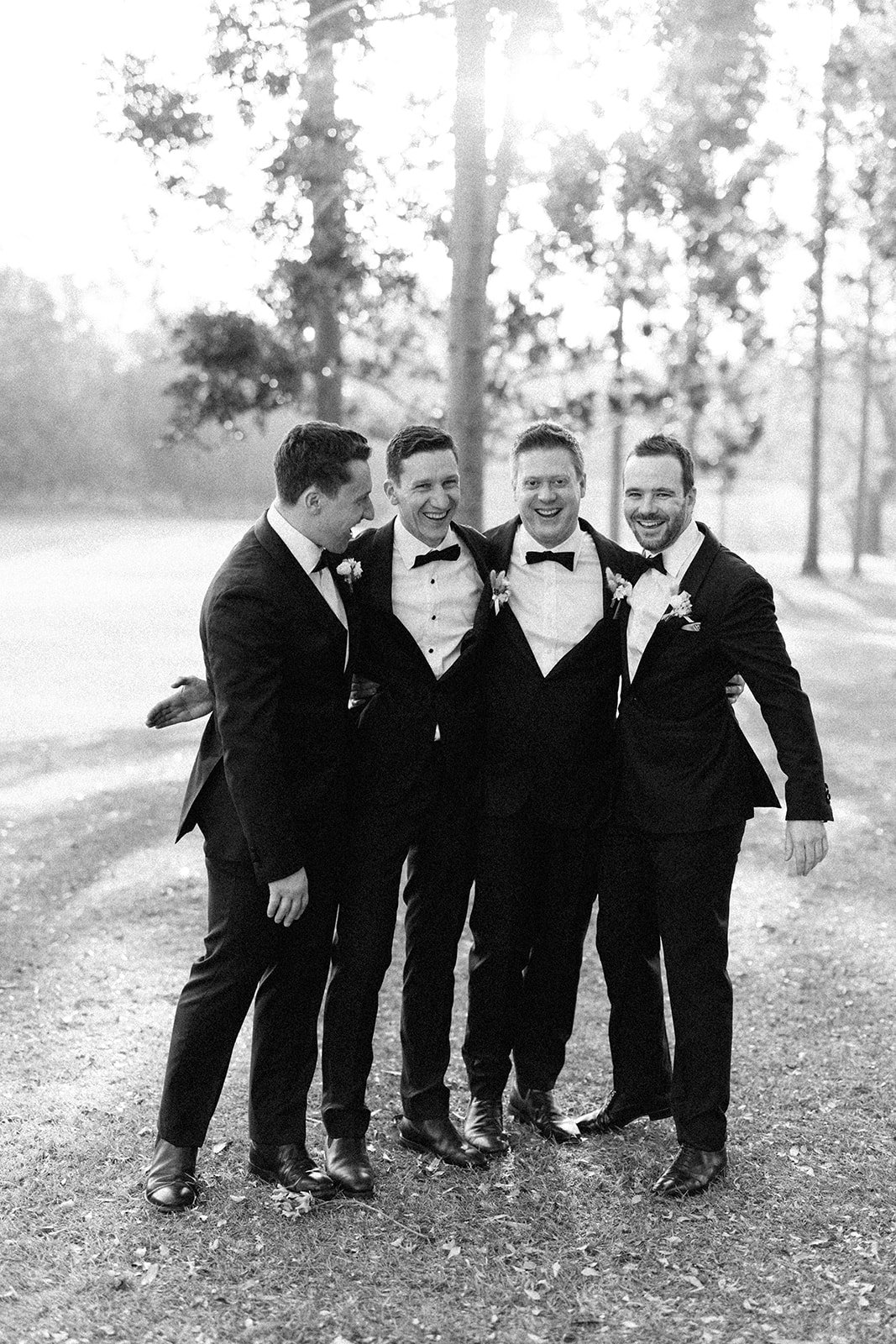 A black and white photos of the groom and groomsman hugging