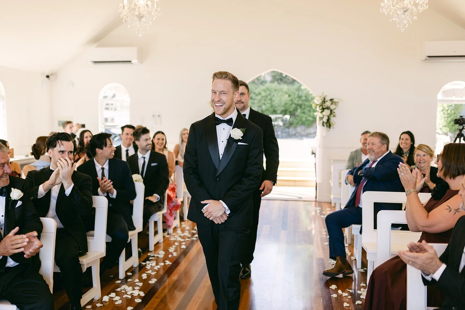 Groom walking down aisle smiling at camera