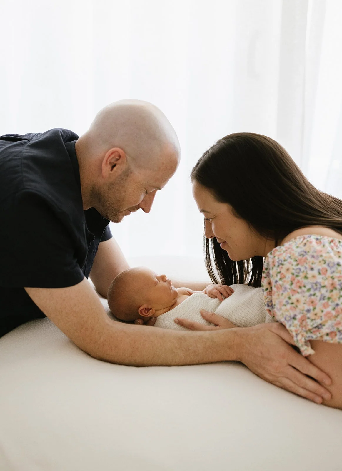 Mother and father holding newborn baby and smiling