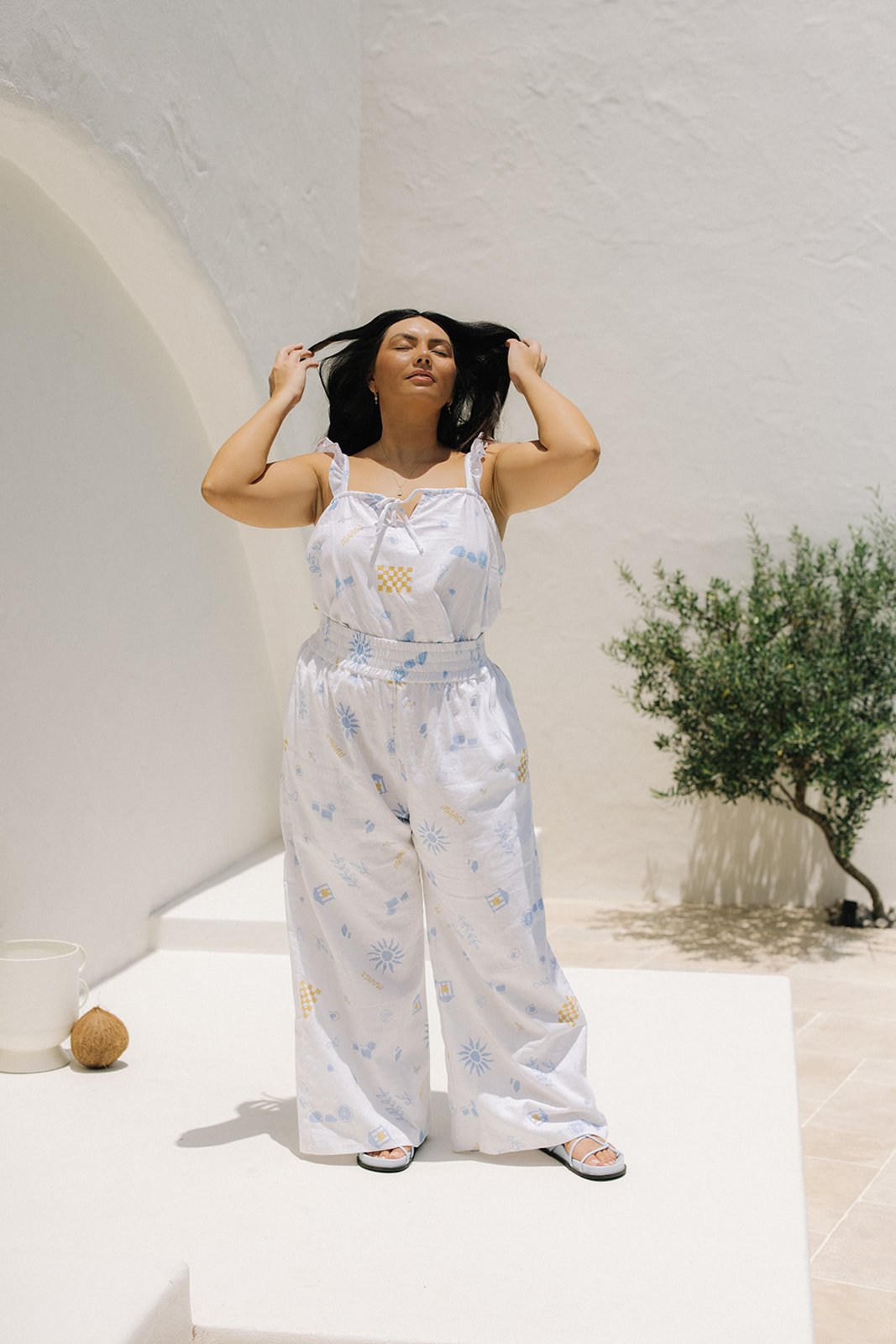 A woman with dark hair wearing a two piece white outfit.