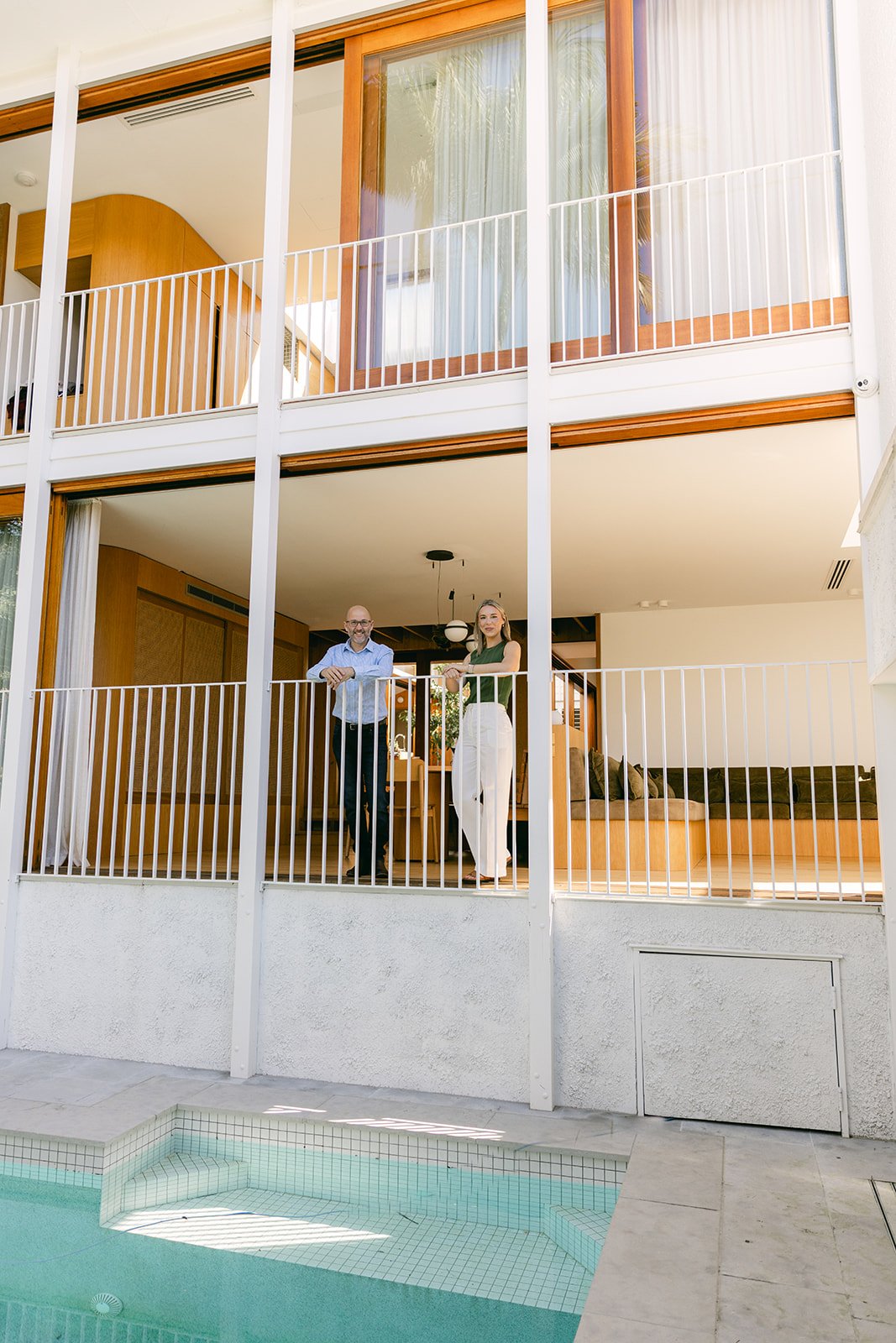 A man and woman are looking over the balcony from a realestate photoshoot