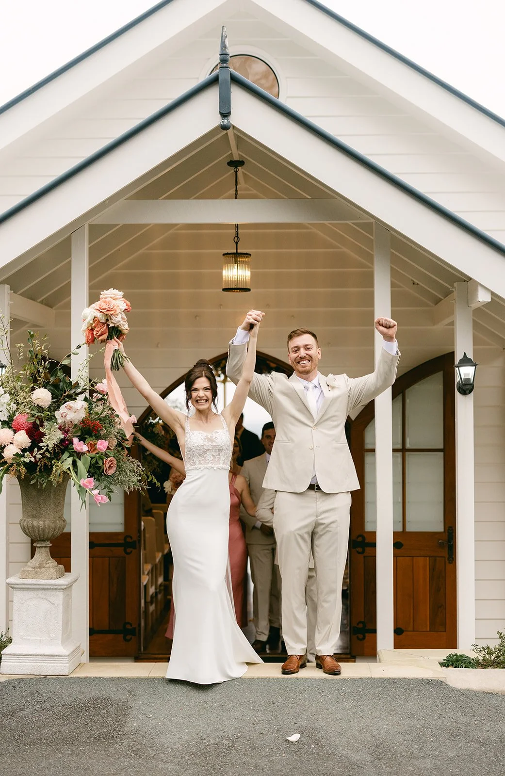 Bride and groom celebrating in-front of wedding ceremony venue.