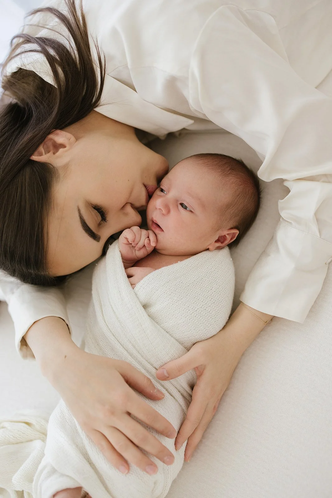 Mother holding newborn baby and kissing baby's cheek
