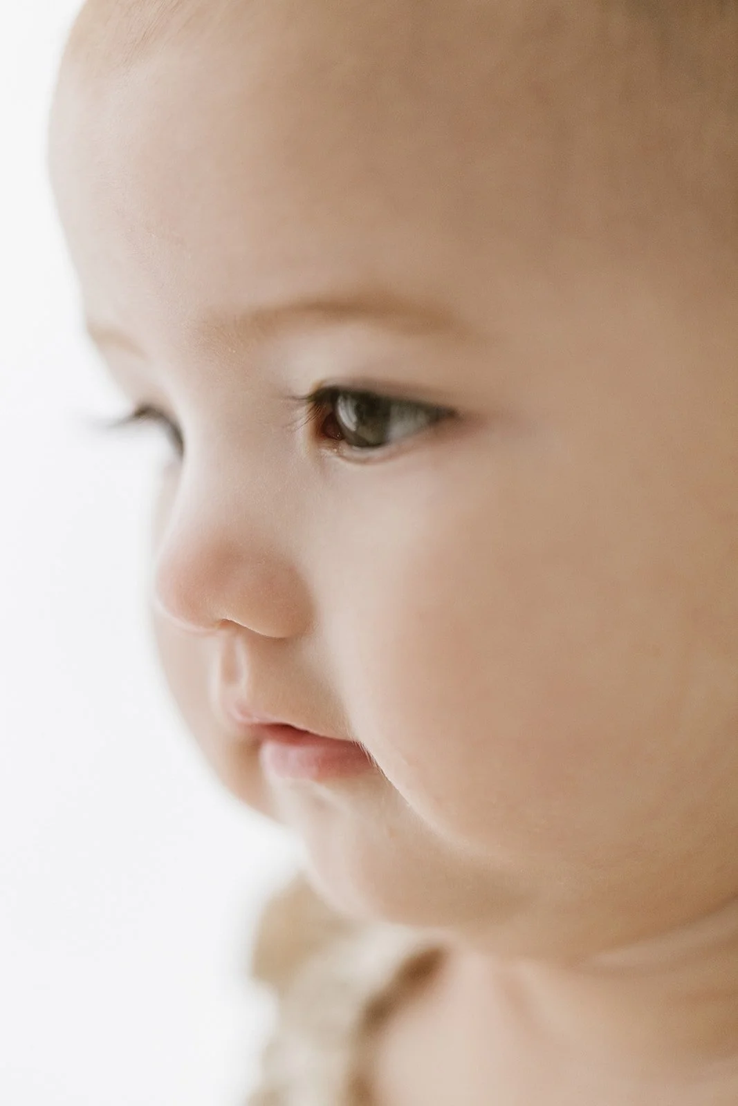 Close-up of a young child's face in profile, showing soft skin, a small nose, and partially visible eyes. Taken at Wylde Folk Studio - Brisbane baby photography.
