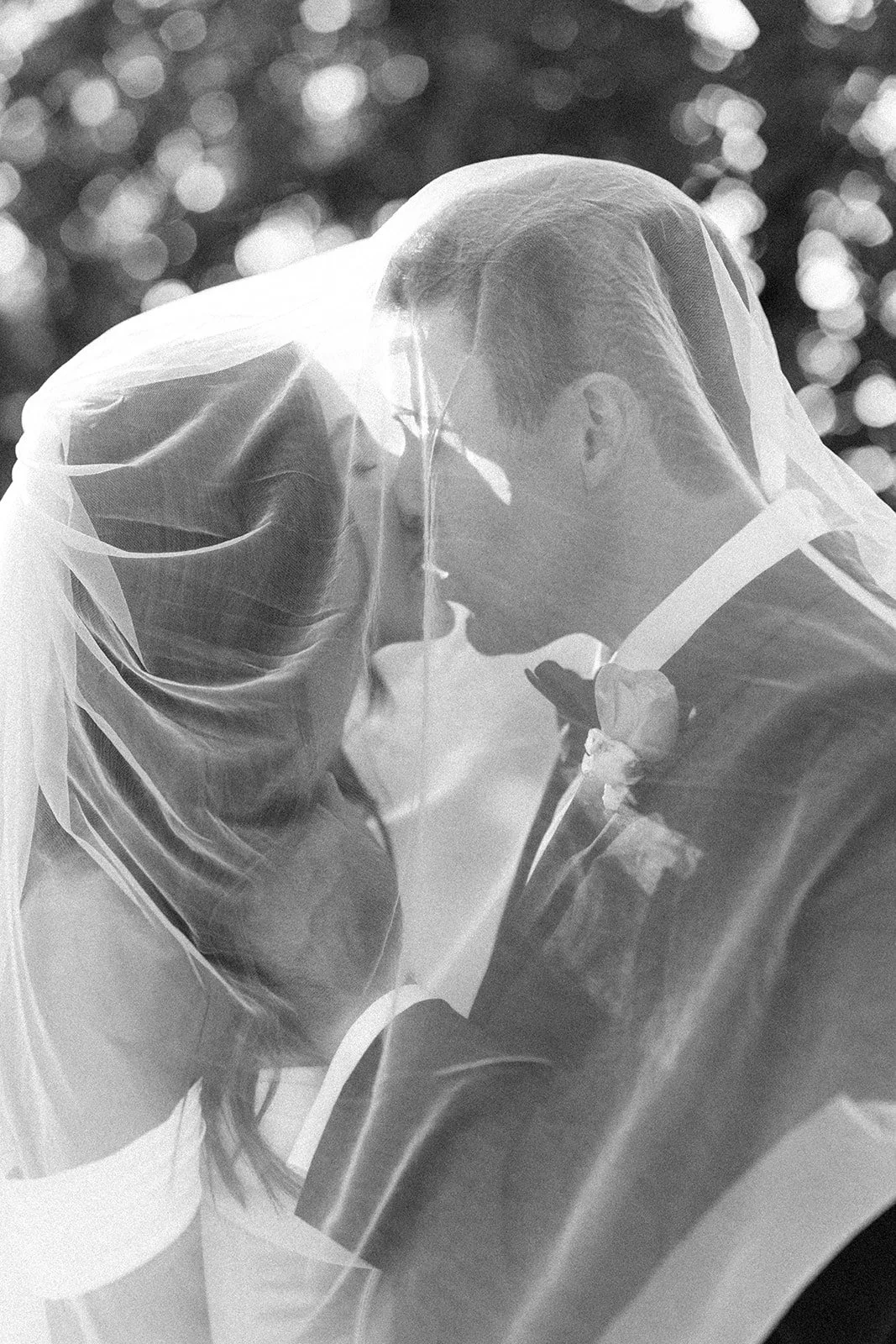 Bride and groom kissing underneath bride's veil