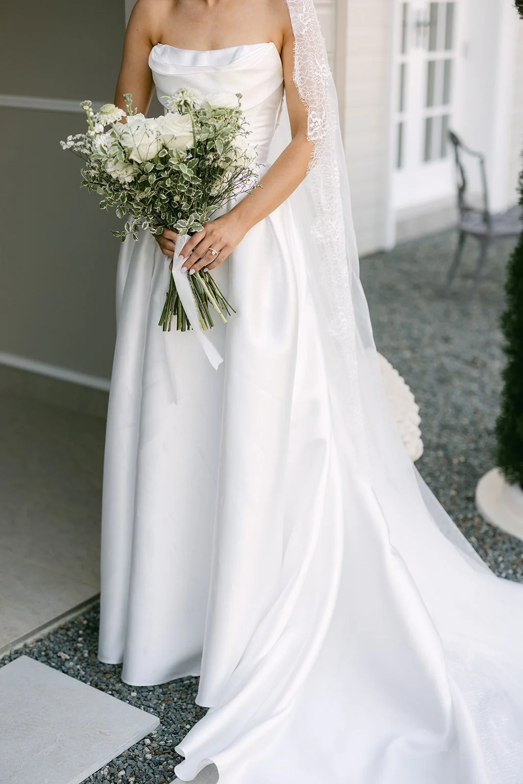 Close-up of Bride's wedding dress and white bouquet
