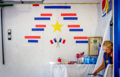 Eveline LeBlanc emerges with a cooler to pack traditional Acadian food for her expat relatives in Toronto and the end of an Acadian feast. Eveline and her husband Martin invite their extended family to enjoy an evening of traditional Acadian food at their house in Memramcook, NB, every August 14. On the wall shows the lineage of both Matin and Eveline's families and how they are actually related 10 generations back.