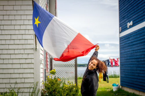 Chantal Cadieux shows off an Acadian flag hanging from her cottage in Shediac Cape, NB. According to Cadieux, the house is over 250 years old and was built by early Acadian fur traders.