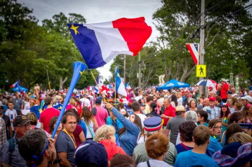 A woman raises her Acadian flag above the crowd during the 2016 Tintamarre in Caraquet, NB.