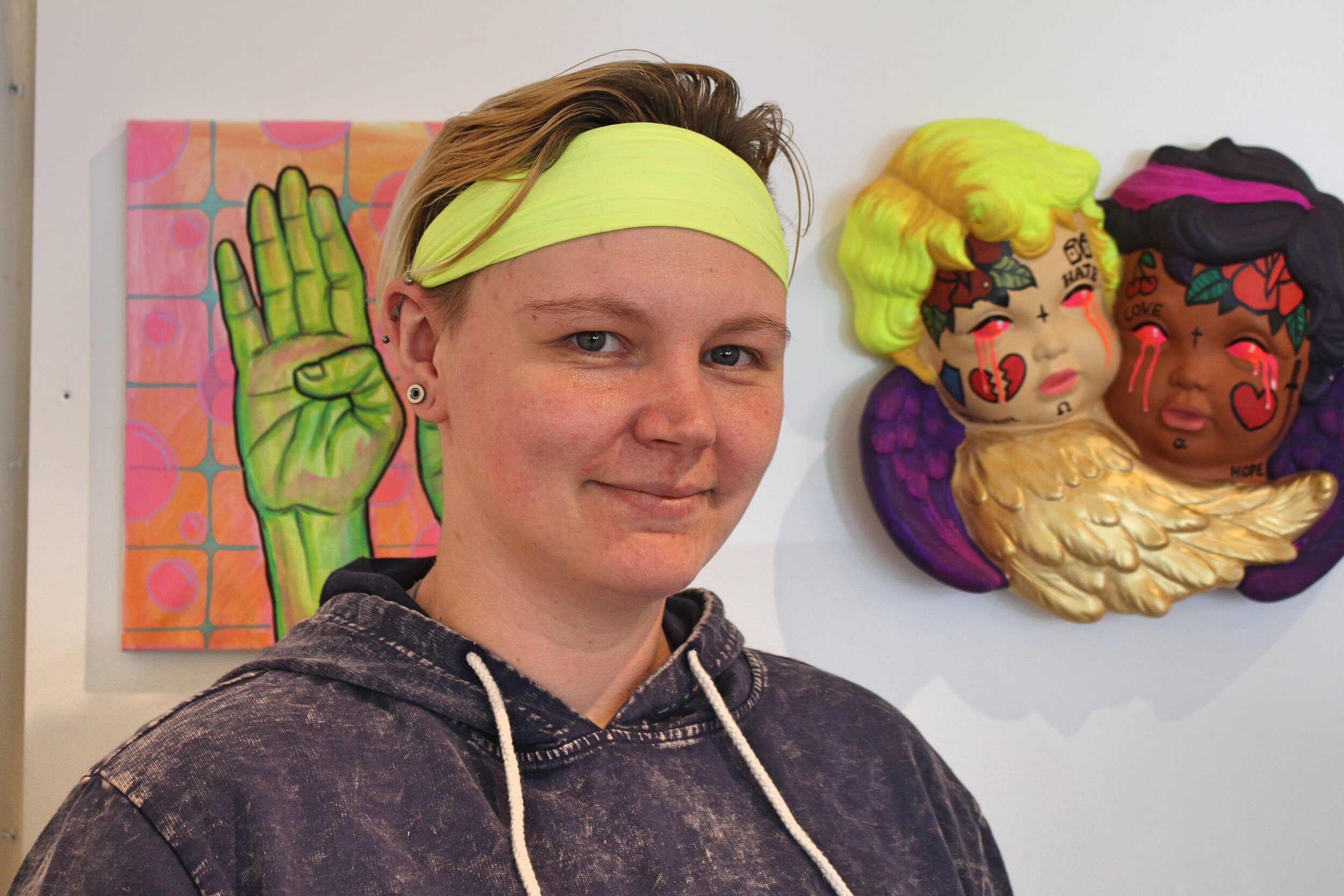  Artist Linsay Nickum stands in front of their pieces  1981(Soap)  [left] and  Chiaroscuro  [right]. Photo by Jerry-Faye Flatt. 