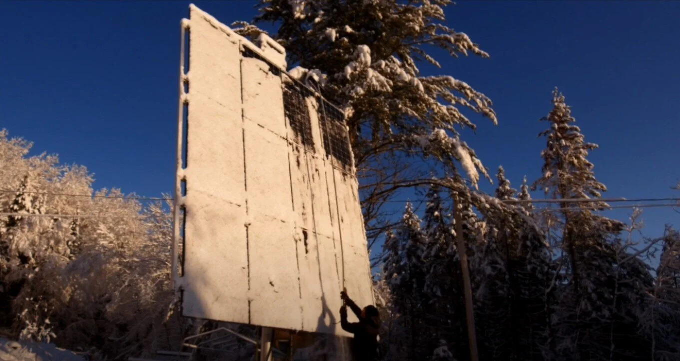 Drew scrapes snow off solar panels. Screenshot from “ Solar Life Episode 8 Panel Adjustment Experiment. ”