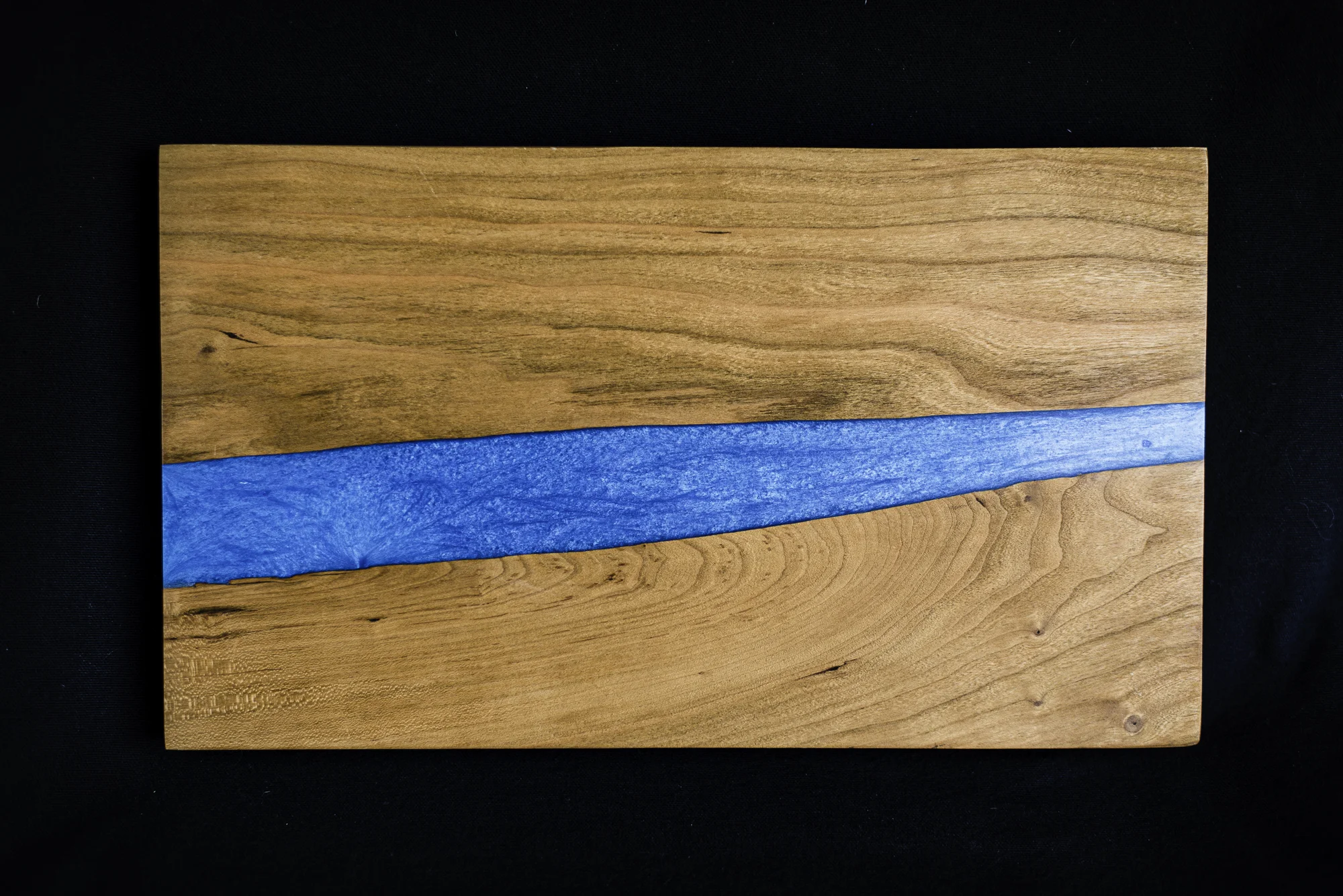 Custom woodworking cherry blue epoxy river serving board
