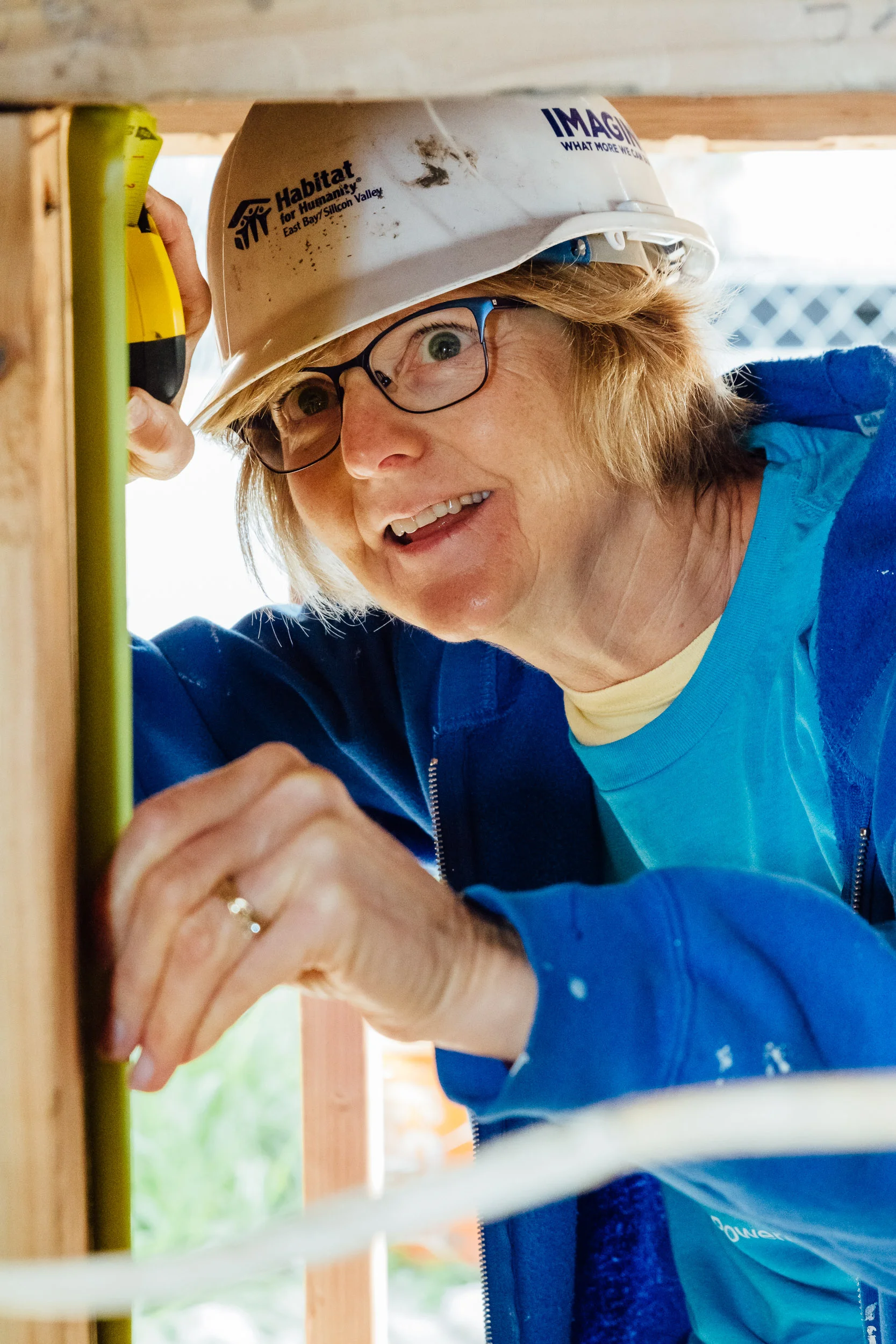 Volunteer measuring a wall frame during a Habitat for Humanity build by Lor Photo