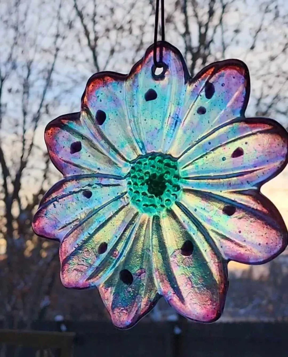 Hand-sculpted iridescent glass memorial flower with a vibrant green and purple Sacred Trace infusion, designed as a sun-catching tribute for a home or garden sanctuary.