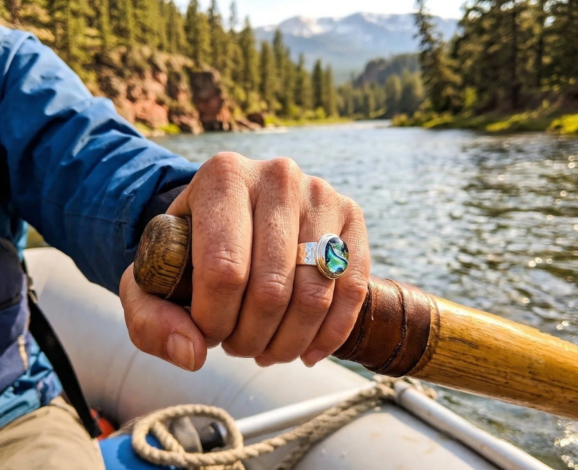 Hand wearing a gold and silver memorial ring on a Montana river.