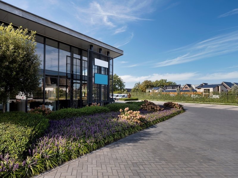 Contemporary commercial building with glass facade landscaped gardens and paved driveway entrance.jpeg