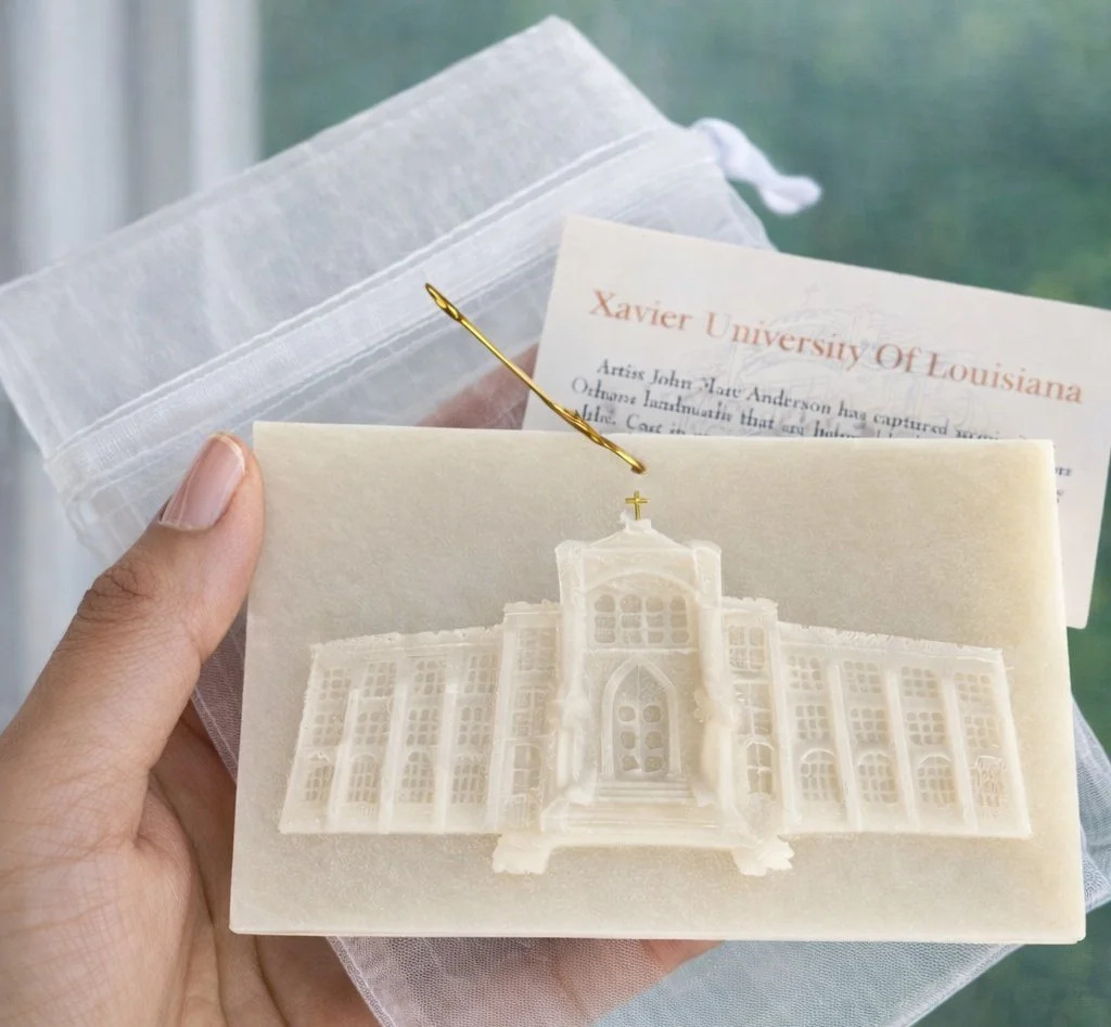 A woman is holding a handcrafted crystal quartz resin memento of Xavier University of Louisiana’s historic administration building, about 3×6 inches, with subtle texture and gold accents, captured against a soft, neutral background.