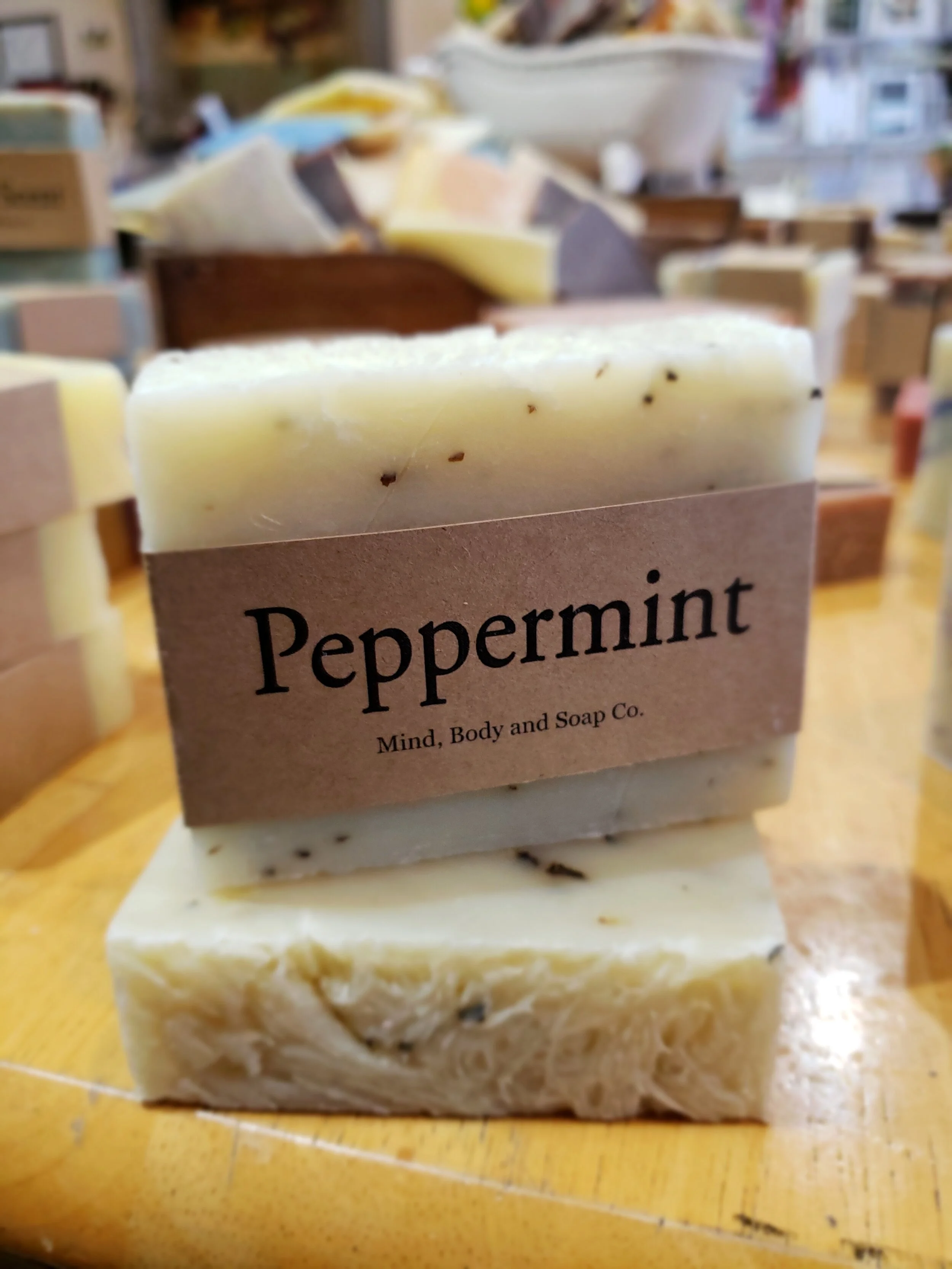 A photo of a rectangular block of soap with a tan label wrapped around it. The soap is a creamy color with a smooth surface and has a simple design.