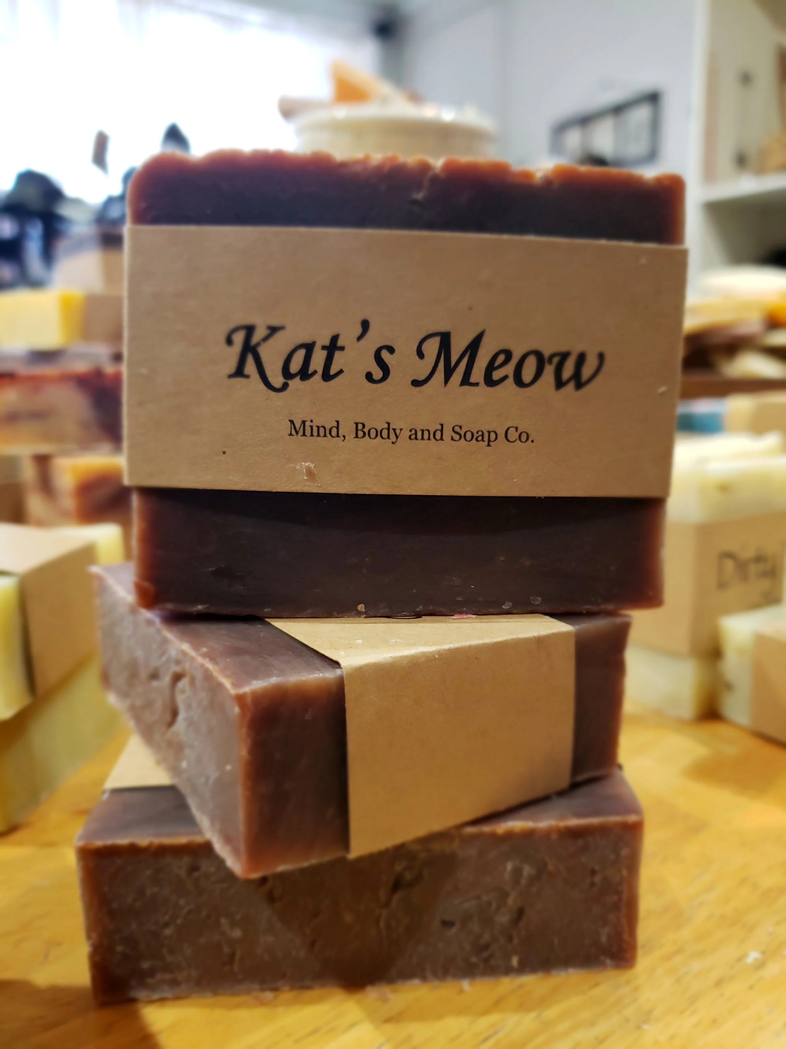 A photo of a rectangular block of soap with a tan label wrapped around it. The soap is a creamy color with a smooth surface and has a simple design.