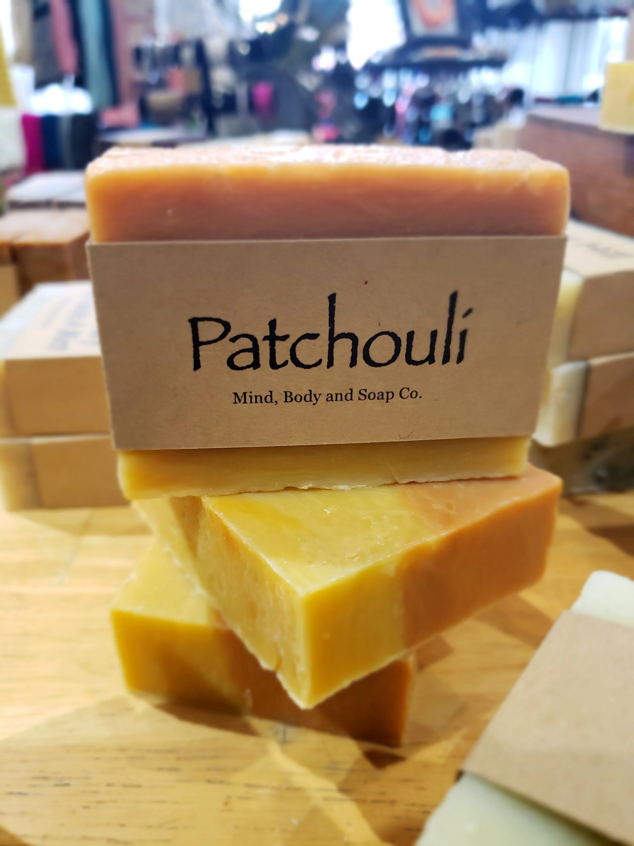 A photo of a rectangular block of soap with a tan label wrapped around it. The soap is a creamy color with a smooth surface and has a simple design.