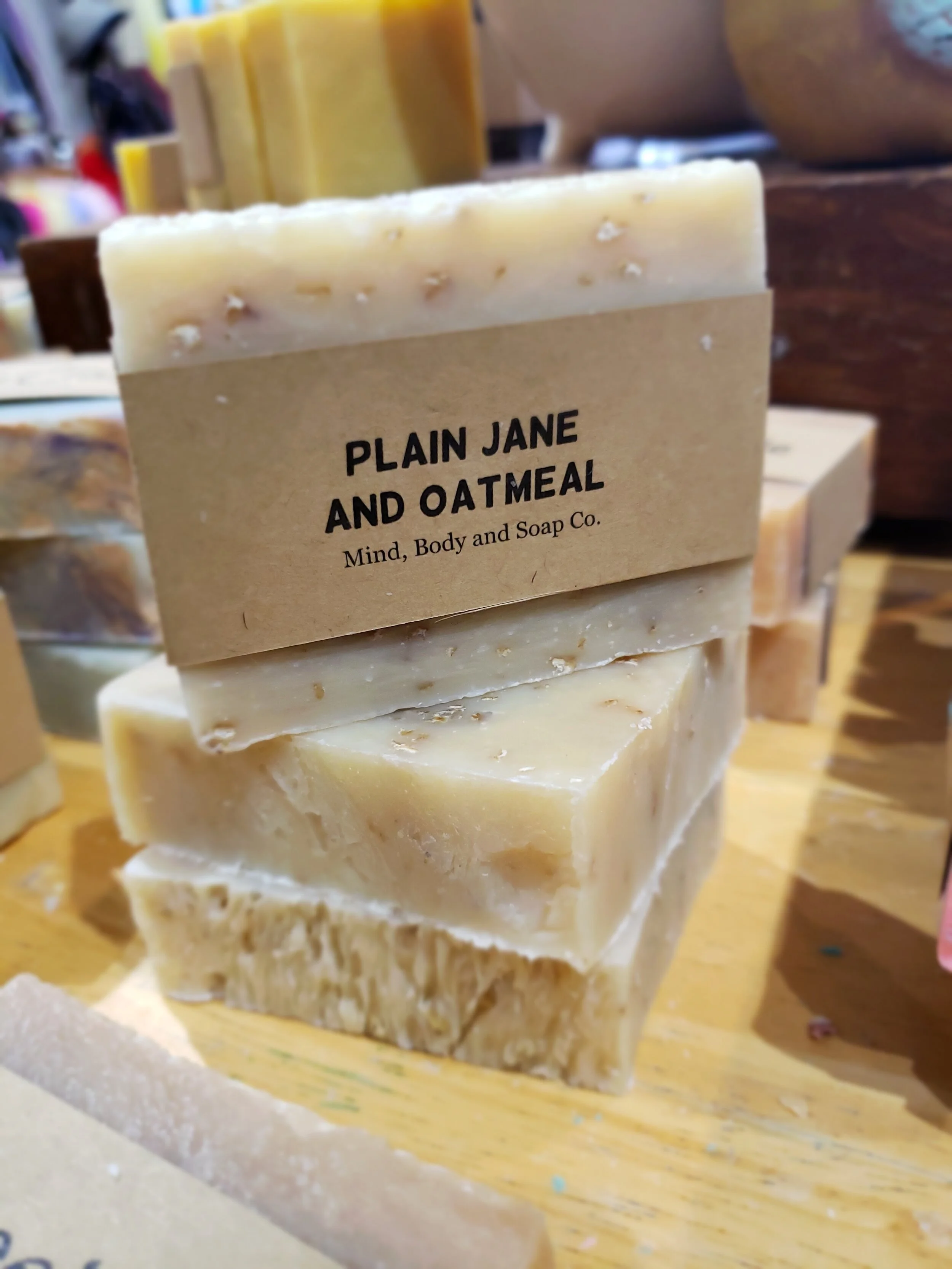 A photo of a rectangular block of soap with a tan label wrapped around it. The soap is a creamy color with a smooth surface and has a simple design.