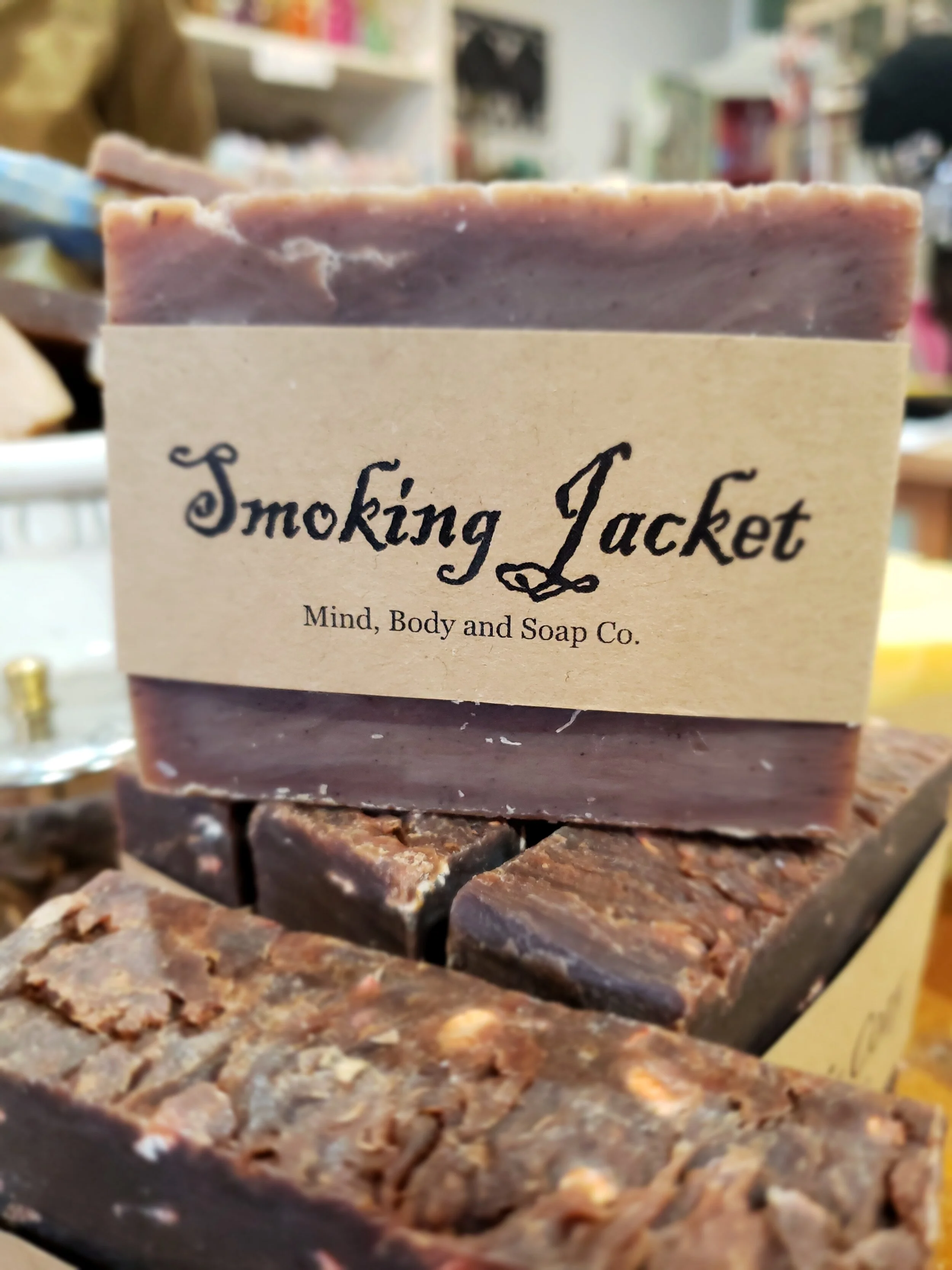 A photo of a rectangular block of soap with a tan label wrapped around it. The soap is a creamy color with a smooth surface and has a simple design.