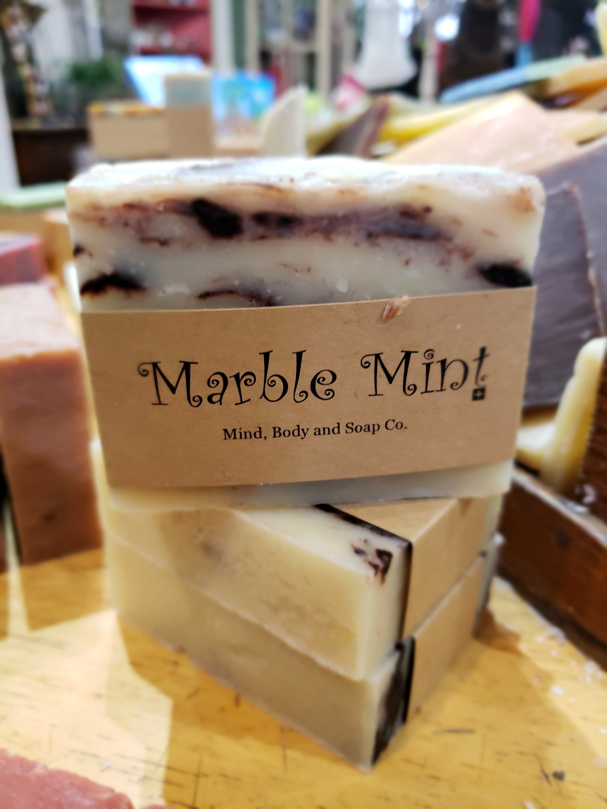 A photo of a rectangular block of soap with a tan label wrapped around it. The soap is a creamy color with a smooth surface and has a simple design.
