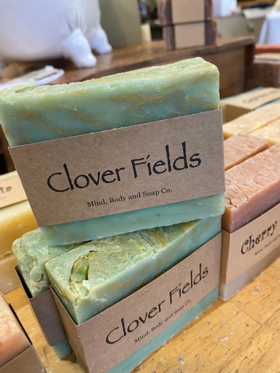 A photo of a rectangular block of soap with a tan label wrapped around it. The soap is a creamy color with a smooth surface and has a simple design.