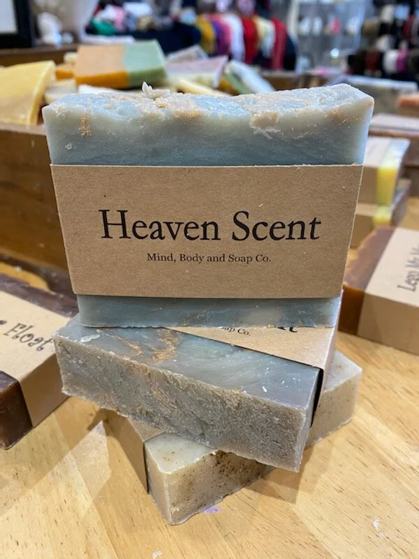 A photo of a rectangular block of soap with a tan label wrapped around it. The soap is a creamy color with a smooth surface and has a simple design.