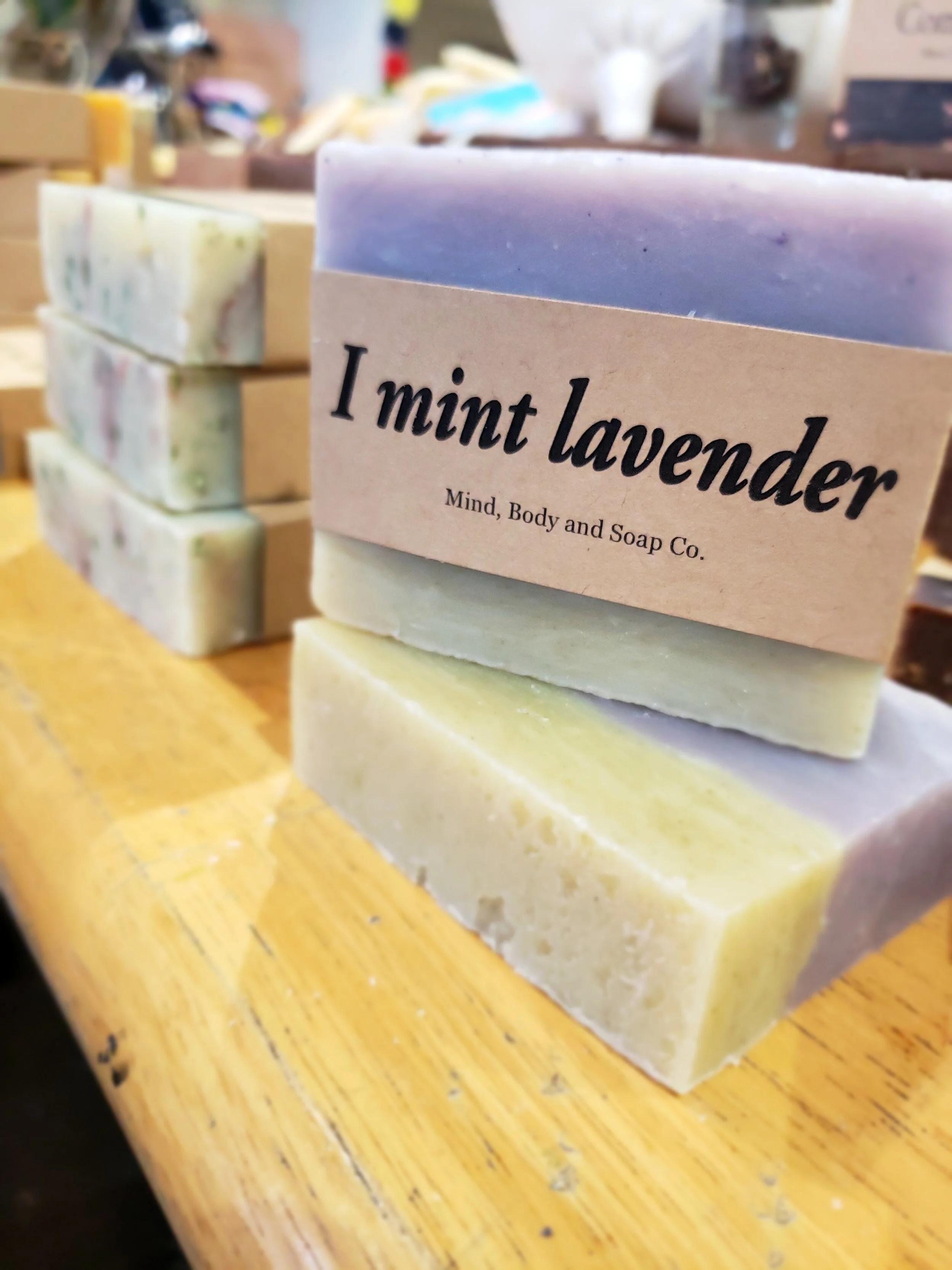 A photo of a rectangular block of soap with a tan label wrapped around it. The soap is a creamy color with a smooth surface and has a simple design.