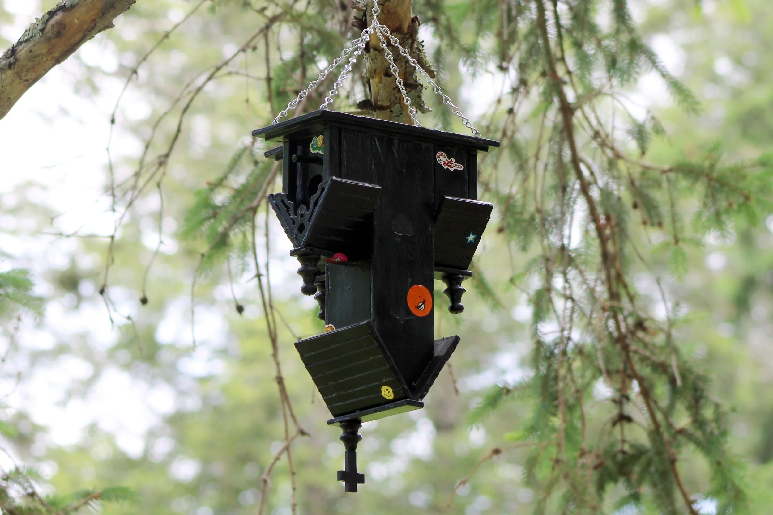  Dovecote  spray paint on found wood birdhouse, stickers, metal chain / 14 × 8.5 × 6.5 in  / 2026  Permanently installed at ChaNorth artist residency, Pine Plains, NY 