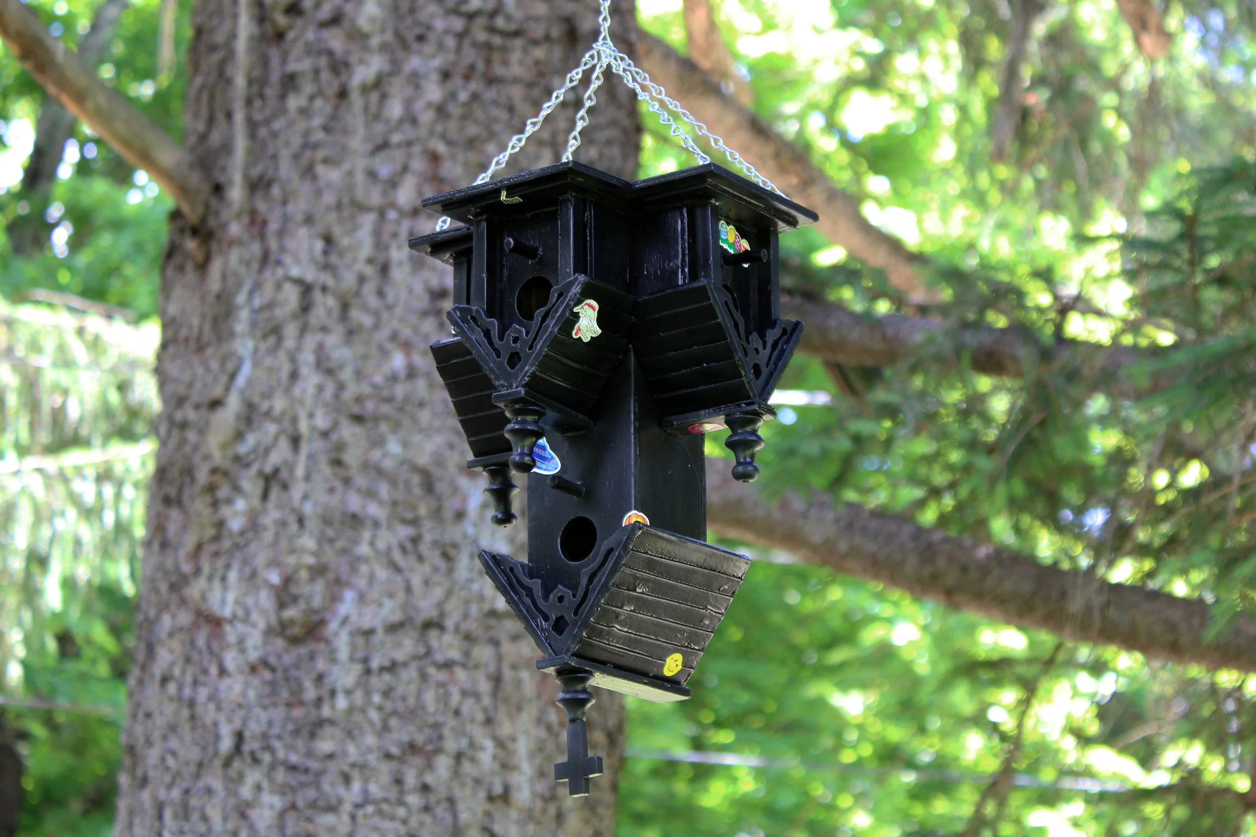  Dovecote  spray paint on found wood birdhouse, stickers, metal chain / 14 × 8.5 × 6.5 in  / 2026  Permanently installed at ChaNorth artist residency, Pine Plains, NY 