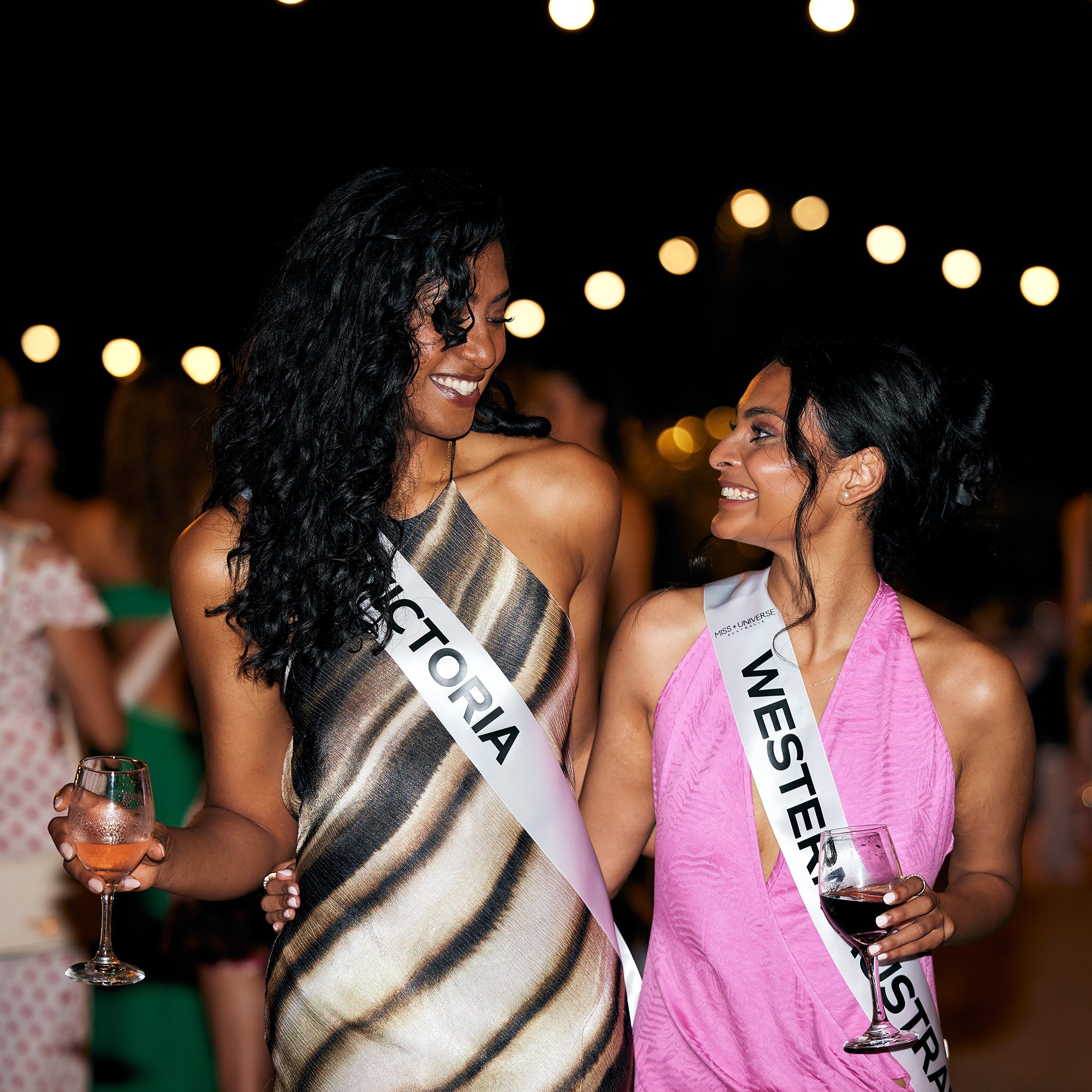 2 women wearing sash's at a beach party