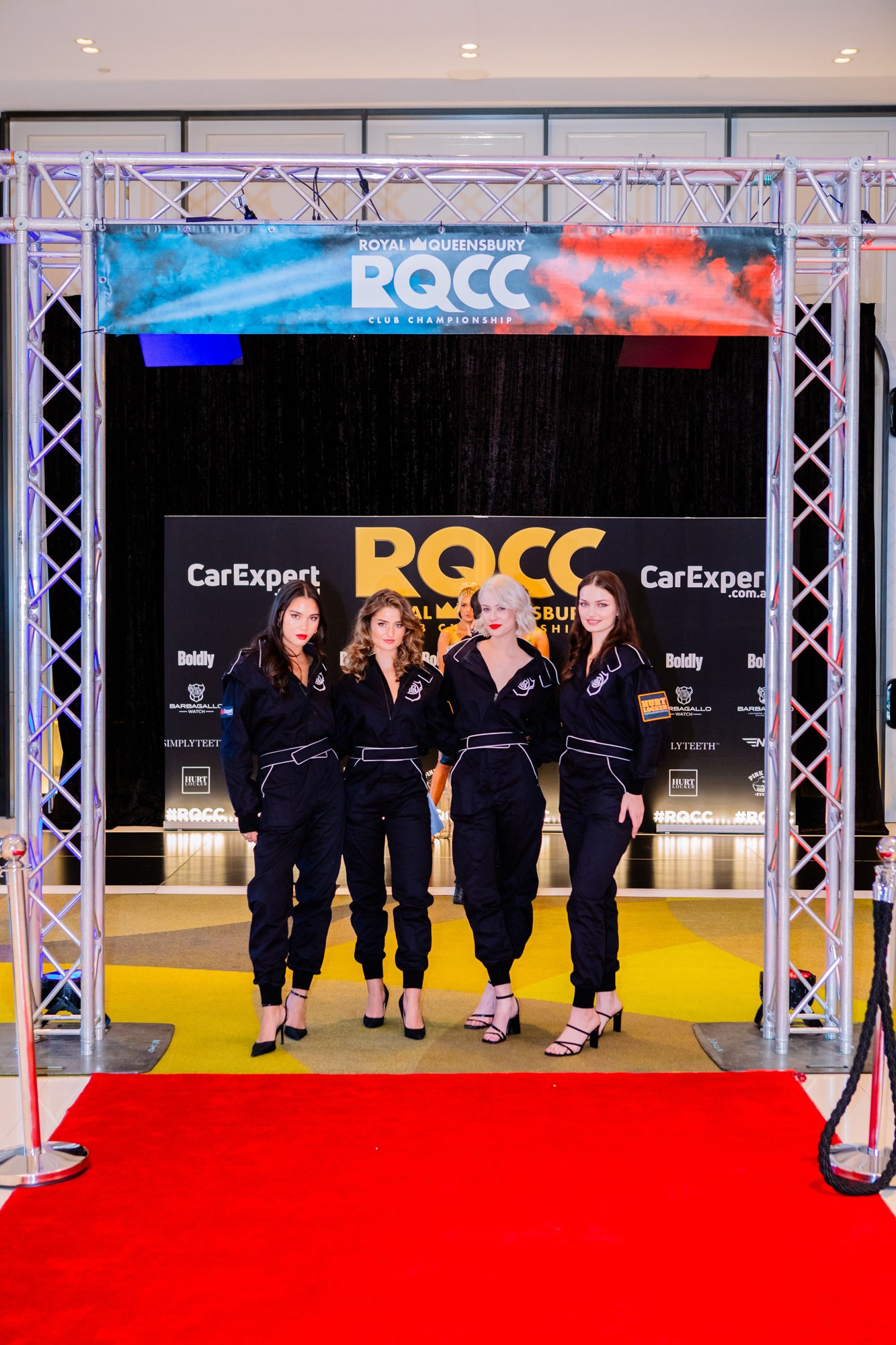 4 women in race suits in front of an event entrance